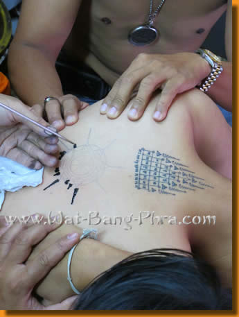 The monk Luang Pi Nunn etches a Yantra Tattoo to a woman